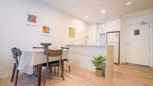 A modern kitchen with white cabinets, a built-in oven, and a dining area with a table and chairs. - Stunning and Serene Two-bedroom Apartment (Auckland)
