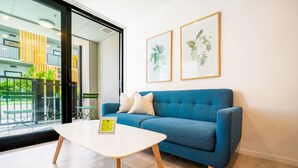A modern room with a blue sofa, a white table, and two framed plant pictures on the wall. - Stunning and Serene Two-bedroom Apartment (Auckland)