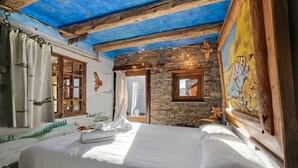 A room with a bed, wooden beams, stone wall, and a mural. - Grange Romantic Retreat Mountain View (Sauze di Cesana)