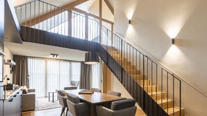 A modern interior with a dining area, kitchen, and staircase.