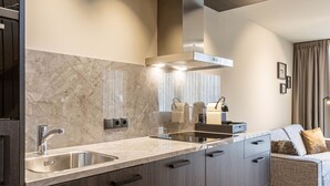 A modern kitchen with a marble backsplash, stainless steel appliances, and a built-in oven.