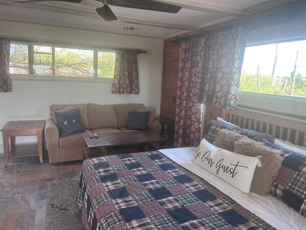 A cozy room with a bed, a sofa, a small table, and a window with curtains.