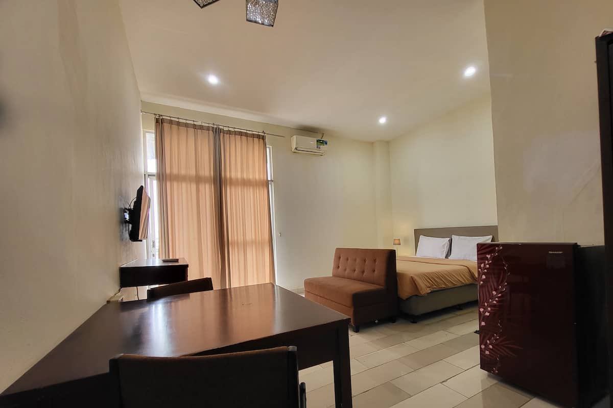 Una habitación de hotel con una mesa de comedor, un sofá, una cama y un refrigerador.
