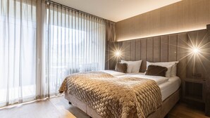 Ein modernes Schlafzimmer mit einem großen Bett, transparenten Vorhängen und einem Holzkopfende.