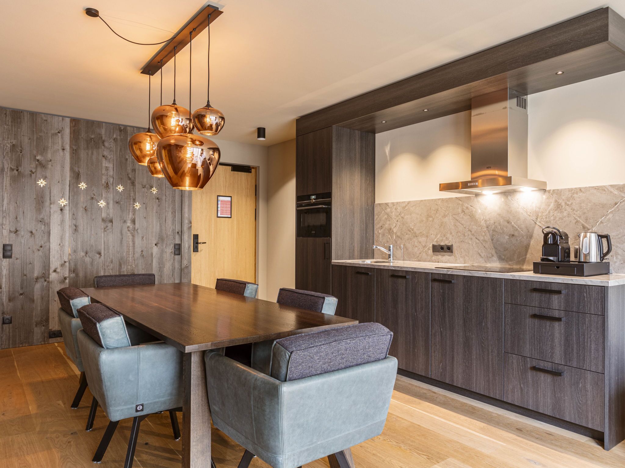 A modern kitchen with dark wood cabinets, a marble countertop, and a built-in oven.