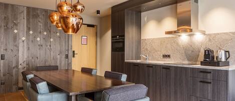 A modern kitchen with dark wood cabinets, a marble countertop, and a built-in oven.