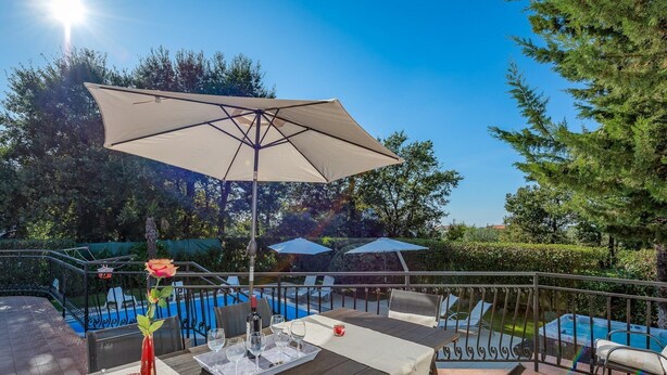An outdoor patio with a table set for dining, surrounded by chairs and a large umbrella.