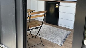 A compact kitchen with white cabinets, a microwave, a coffee maker, and a small window. - The Dacious by Tiny Away (East Feluga)