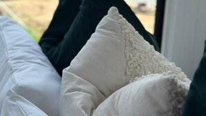 A bed with white and dark green pillows, a view of a lake, and greenery in the background. - The Dacious by Tiny Away (East Feluga)