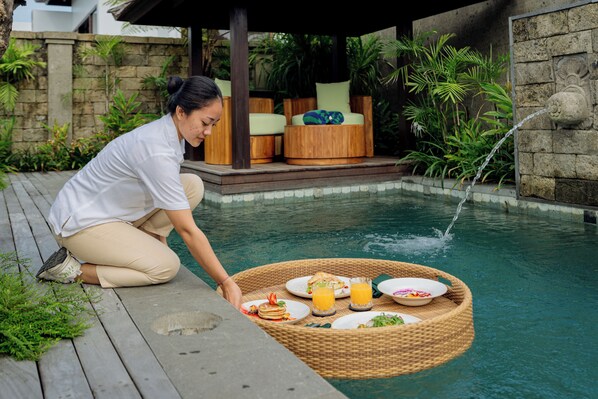 A woman serving breakfast by a poolside with a wicker basket containing plates of food and drinks. - E Sanctuary Resort Ubud (Ubud)