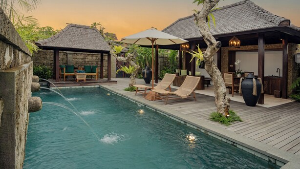 A serene pool area with lounge chairs, a wooden deck, and a stone wall. - E Sanctuary Resort Ubud (Ubud)