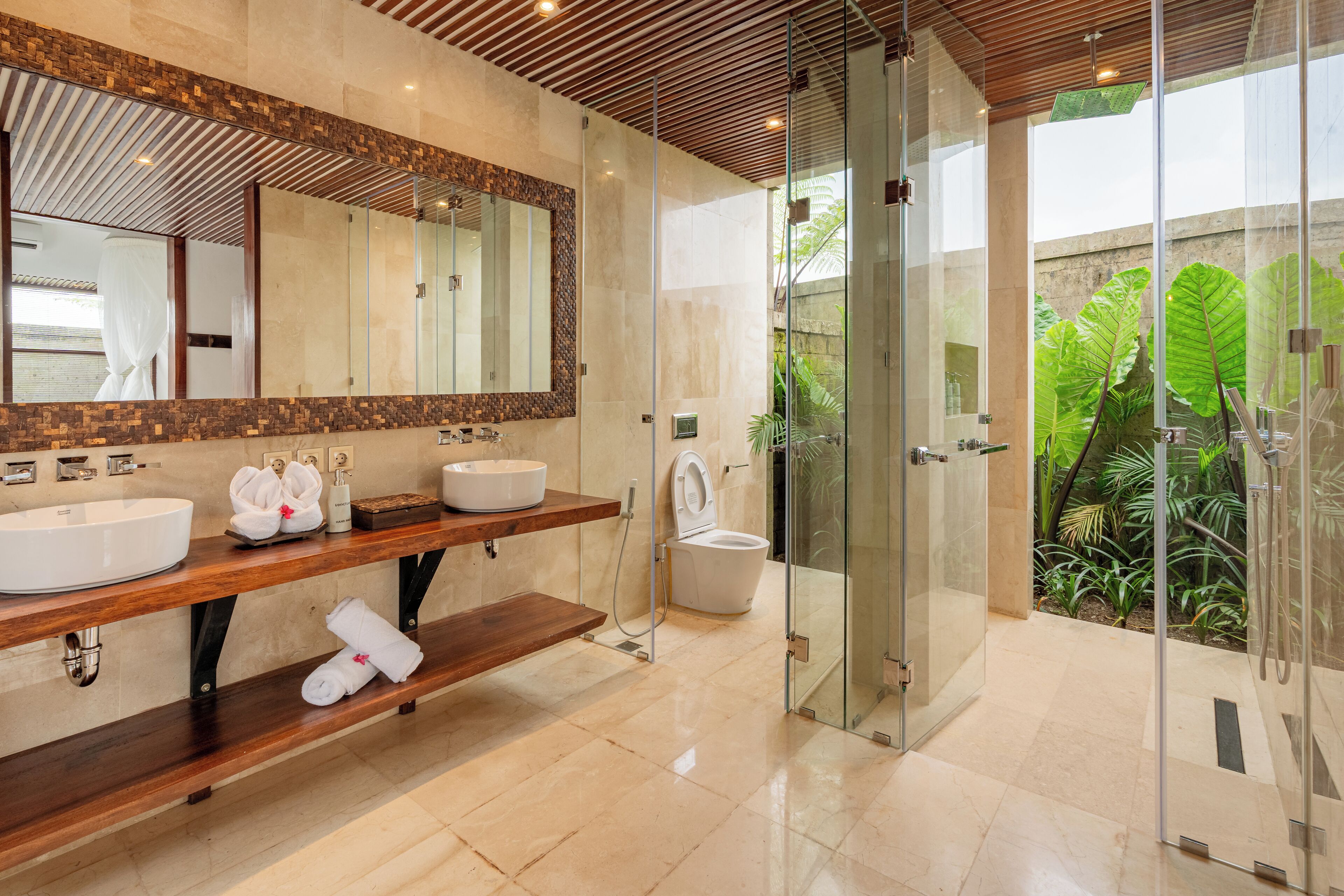 A modern bathroom with two sinks, a large mirror, and a glass-enclosed shower area.