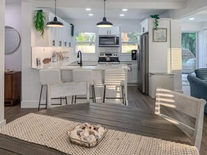 A modern kitchen with white cabinetry, a central island, and pendant lighting.