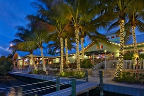A waterfront hotel with palm trees decorated with lights, a covered outdoor area, and a dock. - Surf Chic 3br, Firepit, Boating, Fishing, Beaches (Melbourne)