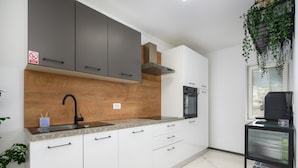 A modern kitchen with white cabinets, a black oven, and a built-in microwave. - Villa in Porec With Private Pool and Beach (Porec)