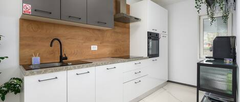 Una cocina moderna con armarios blancos, un horno negro y un microondas integrado.