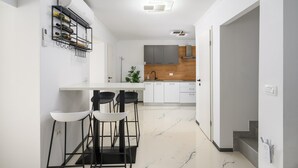 A modern kitchen with white cabinets, a marble floor, and a bar area with stools. - Villa in Porec With Private Pool and Beach (Porec)