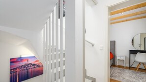A modern interior with a staircase, a cityscape painting, a desk with a chair, and a mirror. - Villa in Porec With Private Pool and Beach (Porec)