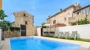 A swimming pool with lounge chairs and a stone building in the background. - Villa in Porec With Private Pool and Beach (Porec)