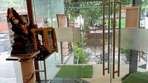 A reception area with a marble column, a framed picture, and a small shrine with flowers. - Hotel Swathi  (New Delhi)