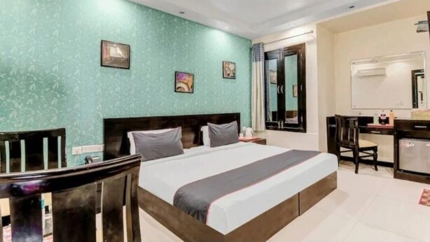 A hotel room with a bed, a desk, and a chair. - Hotel Swathi  (New Delhi)
