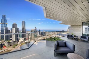 A modern balcony with a city view, furnished with sofas and a table, and a glass railing. - Melbourne Corporate Apartments – Collins Street (Melbourne)