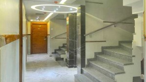 A modern staircase with a marble floor and a circular light fixture above it. - HOTEL IMPERIAL VIEW (New Delhi)