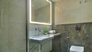 A modern bathroom with a glass-enclosed shower, a vanity with a mirror, and a toilet. - HOTEL IMPERIAL VIEW (New Delhi)