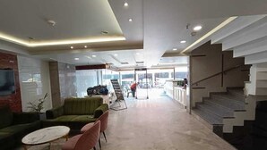 A modern hotel lobby with a seating area, a staircase, and a view of the outside. - HOTEL IMPERIAL VIEW (New Delhi)