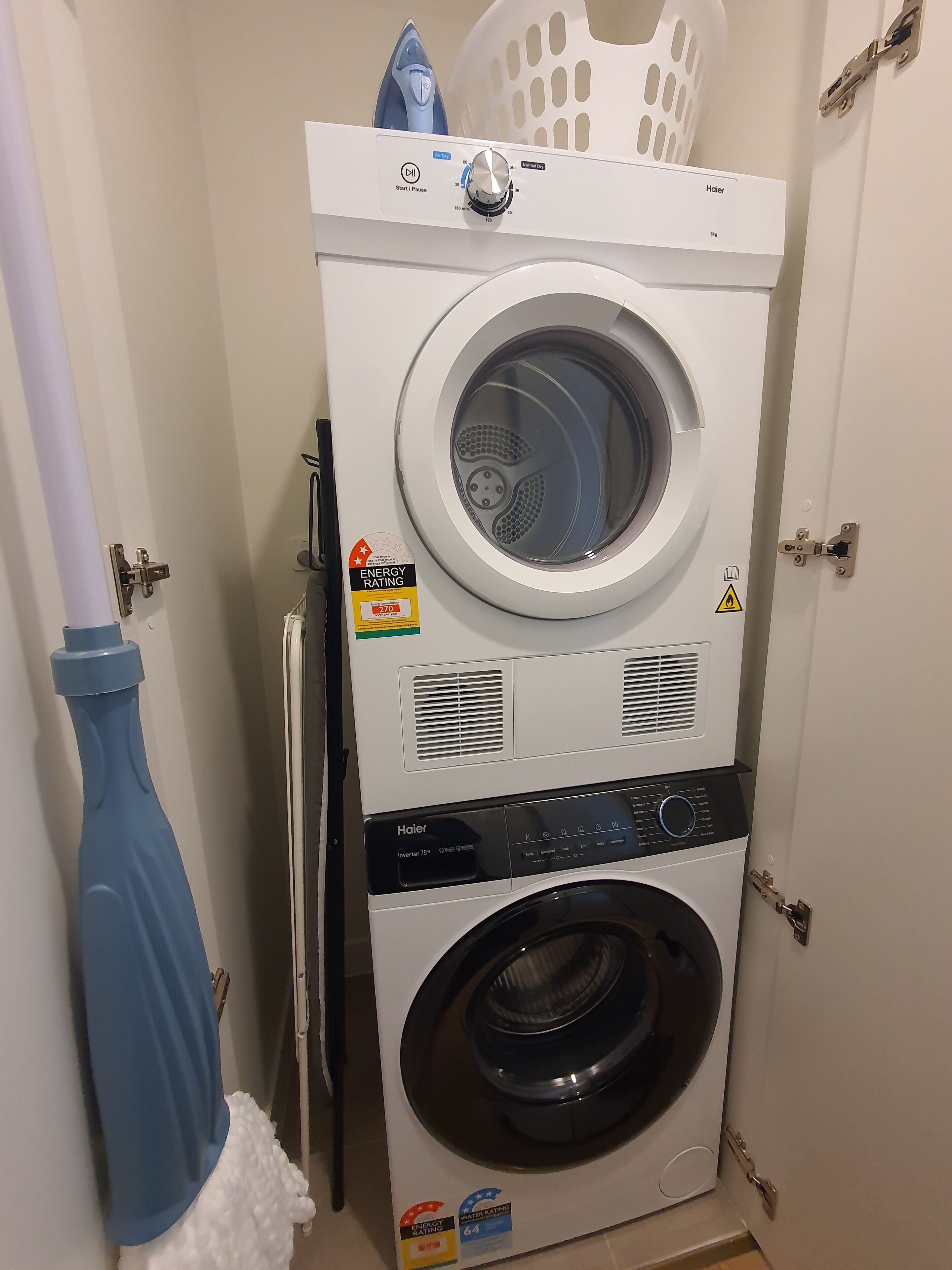 A front-loading washer and dryer unit with an ENERGY STAR rating, a blue bottle, and a white laundry basket.