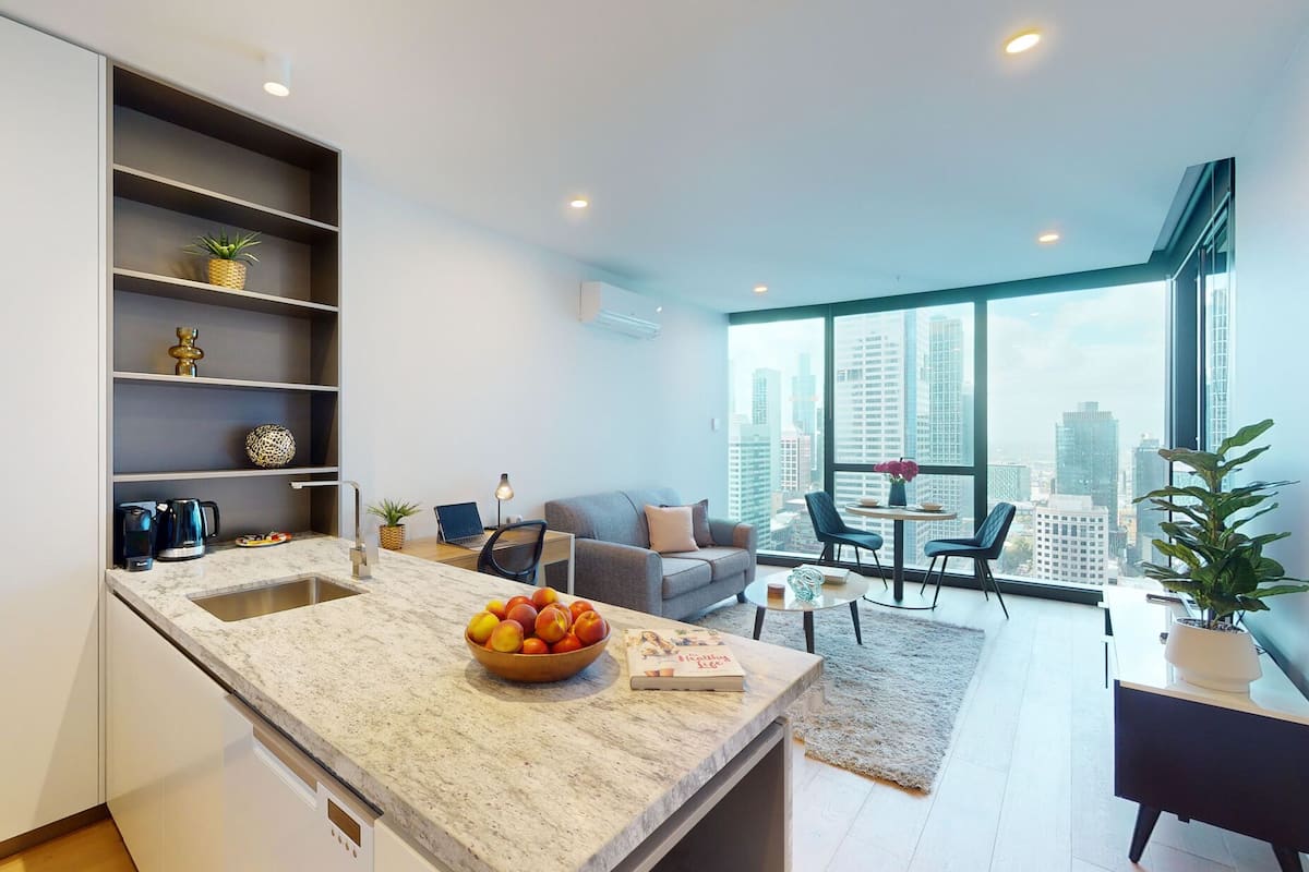 Un apartamento moderno con cocina, comedor y un amplio ventanal con vistas a la ciudad.