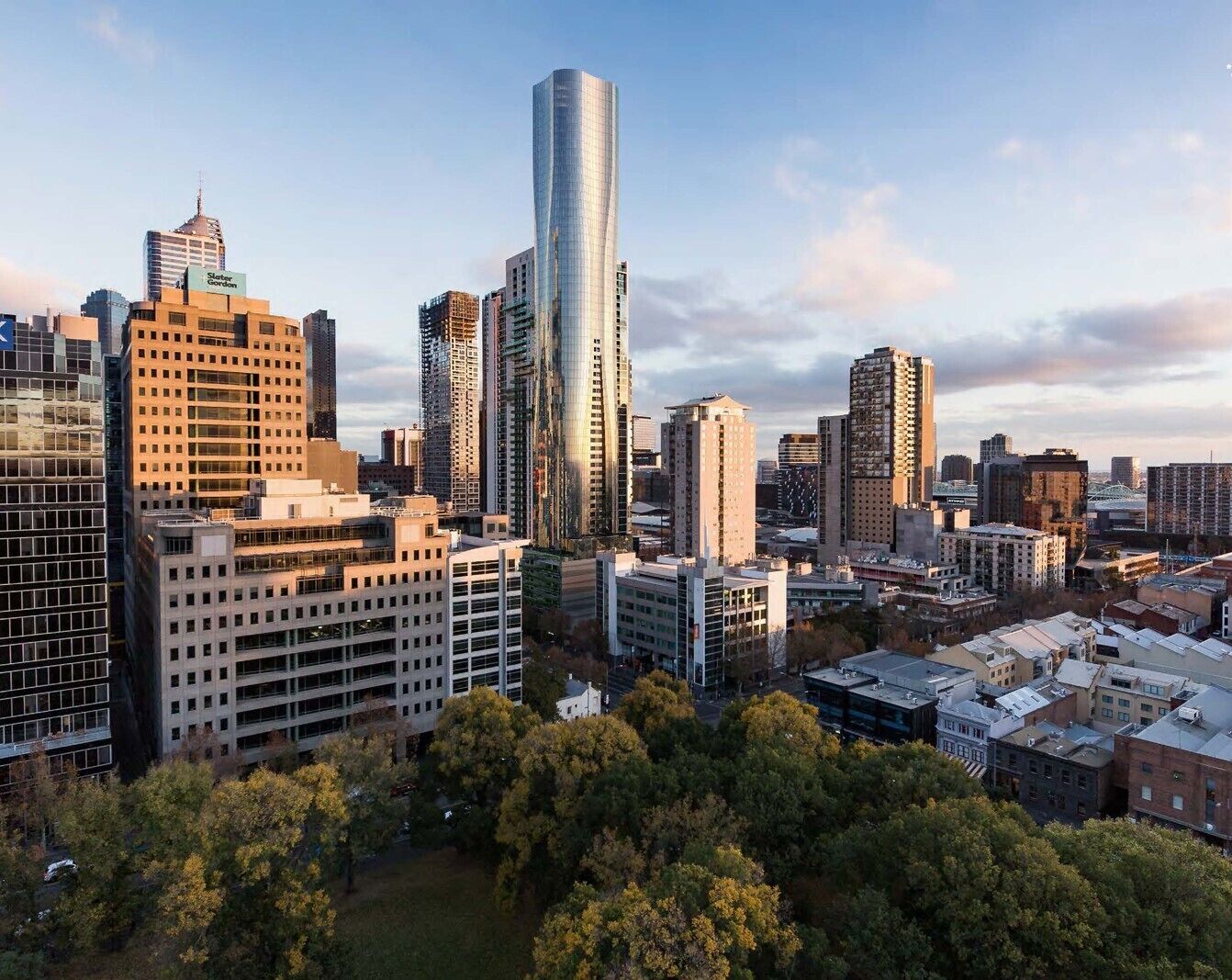 A cityscape with modern high-rise buildings, including a prominent skyscraper with a unique curved design.