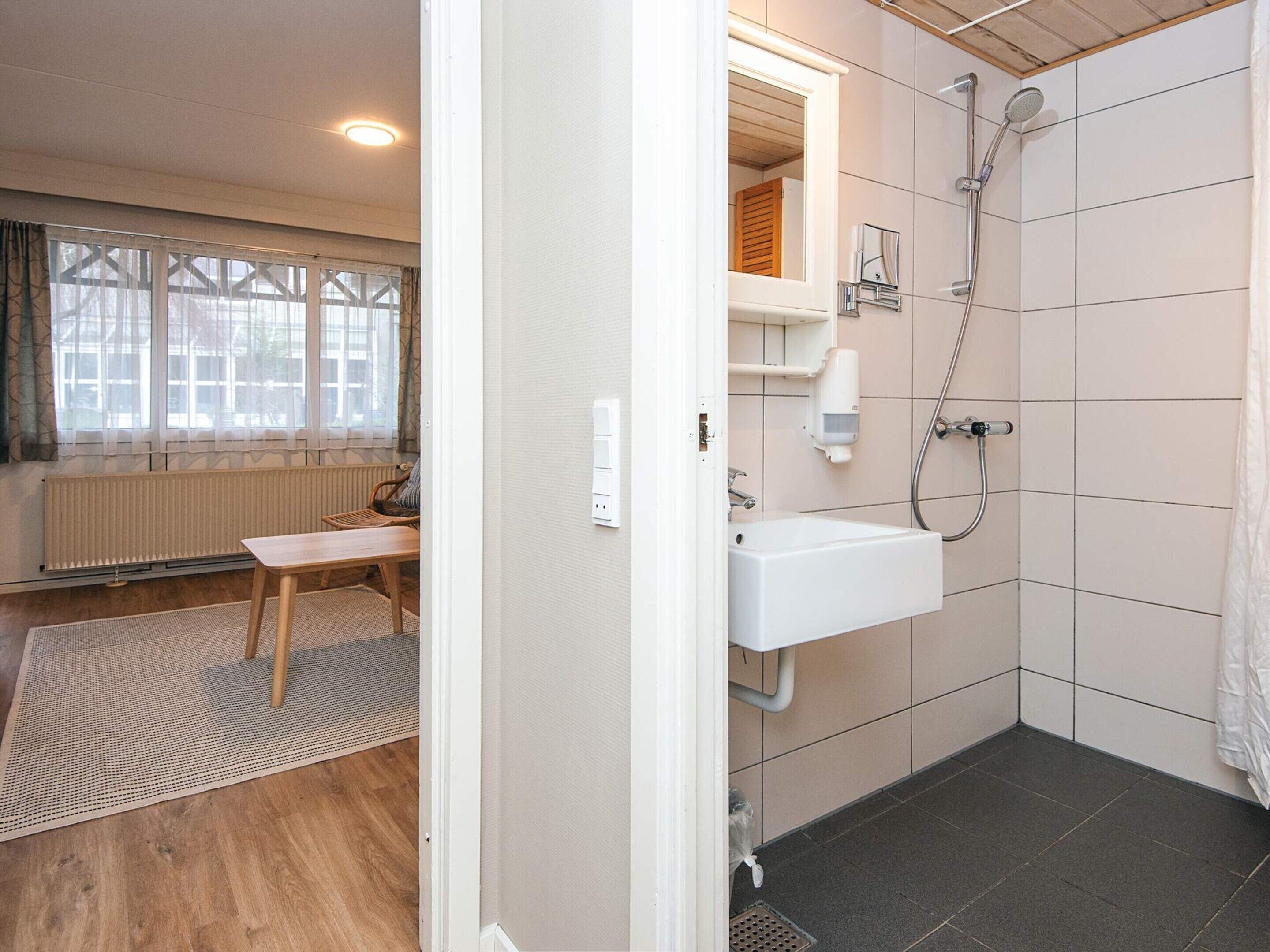 A bathroom with a shower, sink, and window.