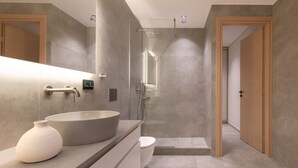 Une salle de bain moderne avec un grand lavabo rond, un miroir et un espace douche.