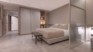 Une chambre à coucher moderne avec un grand lit, un banc, une armoire et un dressing.