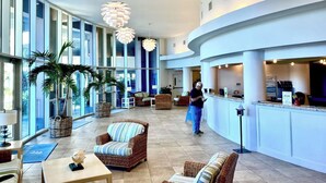 A spacious lobby with wicker furniture, a reception desk, and large windows.