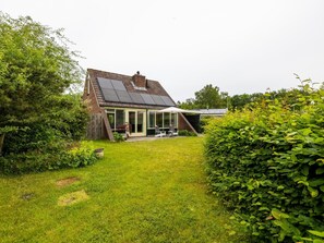 Uma casa com telhado inclinado, uma estufa e um jardim.