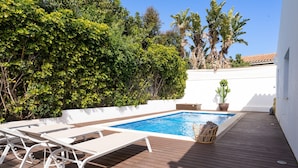 A pool area with white lounge chairs, a wooden deck, and a small potted plant. - Villa in Marbella Near Beach (Marbella)
