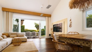 A spacious living area with a large sliding glass door leading to a balcony, a dining table with chairs, and a sofa with cushions. - Villa in Marbella Near Beach (Marbella)