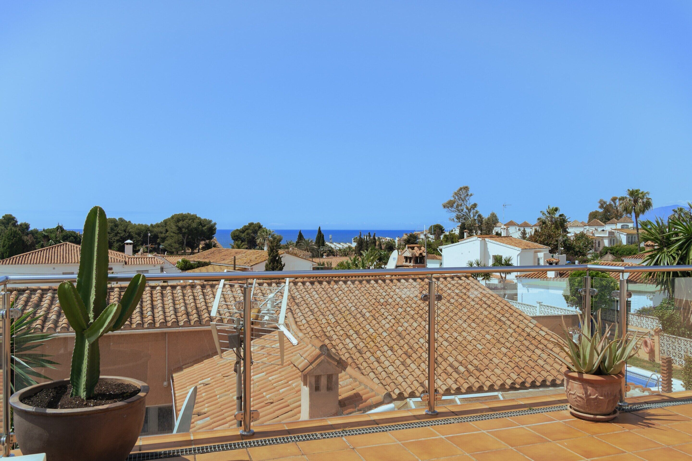 A terrace with a view of the sea, potted plants, and tiled flooring.