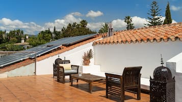 Enjoy panoramic views of the lush landscape from this rooftop retreat, featuring a table and chairs.