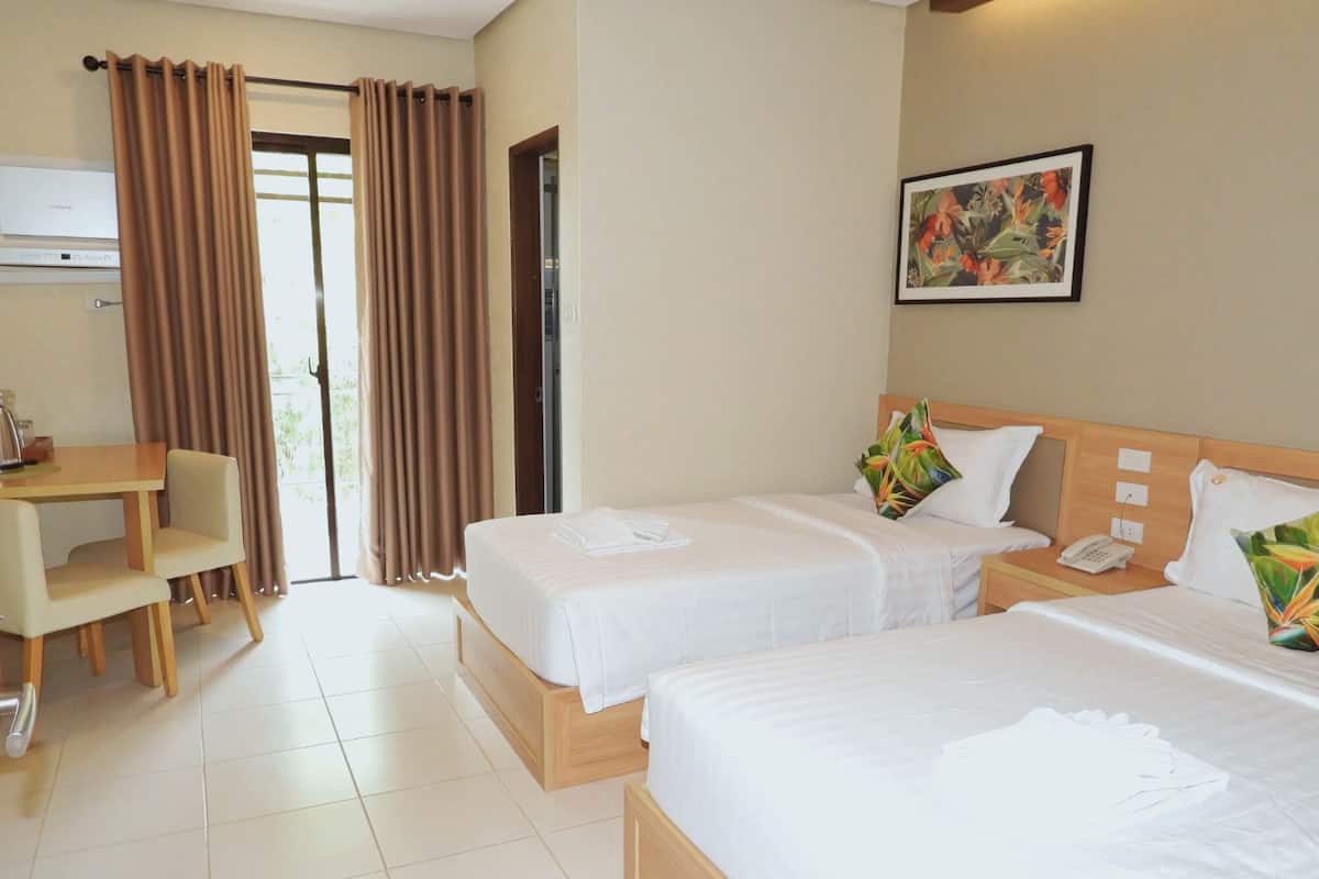 Quarto de hotel com duas camas, uma escrivaninha e uma cadeira.