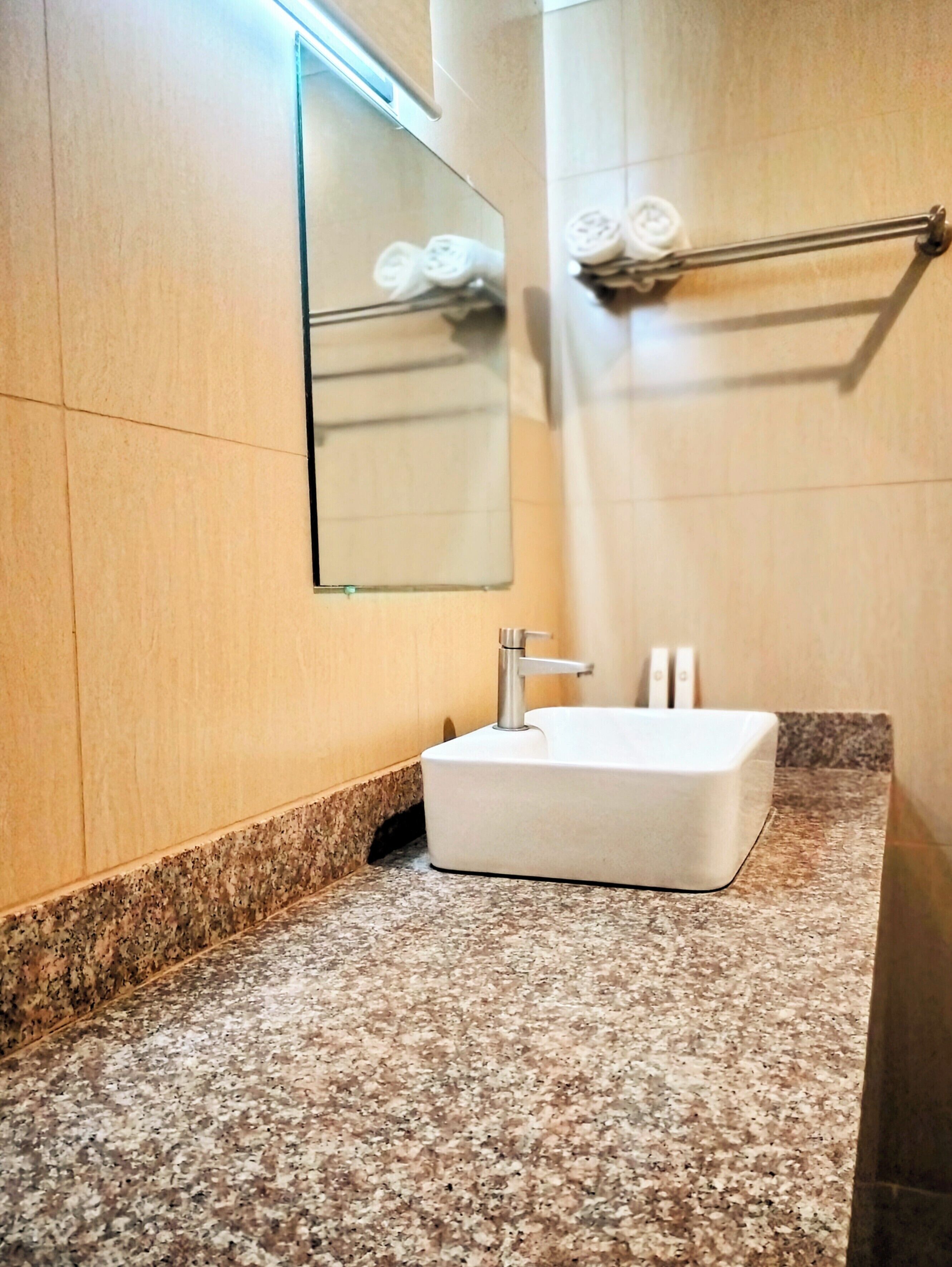 A bathroom with a white sink, a mirror, and a towel rack.