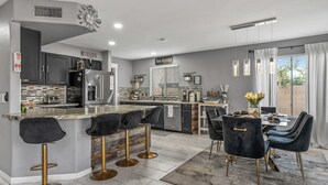 A modern kitchen with a central island, bar stools, and a dining area with a table and chairs. - Spacious 4-bedroom house in charming Avondale with AC, WiFi (Avondale)
