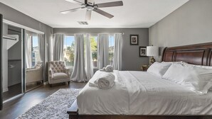 A bedroom with a large bed, a ceiling fan, a chair, and a window with curtains. - Spacious 4-bedroom house in charming Avondale with AC, WiFi (Avondale)