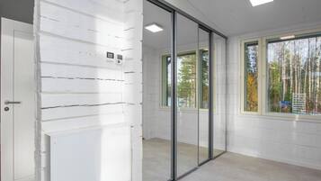 A room with white paneled walls, a sliding glass door, and a view of trees outside.