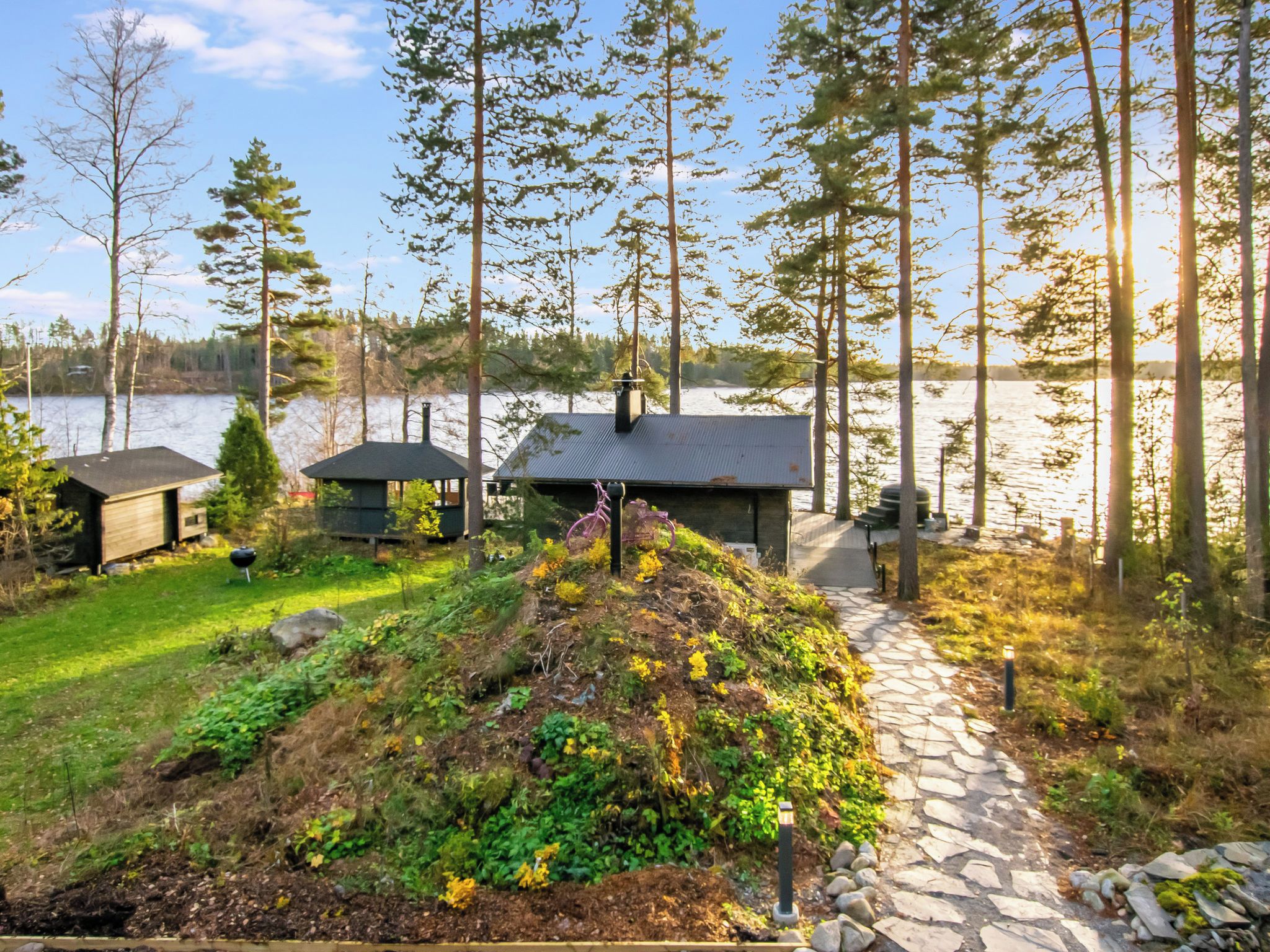 A lakeside cabin with a stone pathway leading to a dock.