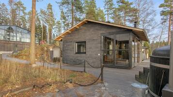 Una cabaña con base de piedra, fachada de madera y grandes puertas de cristal.