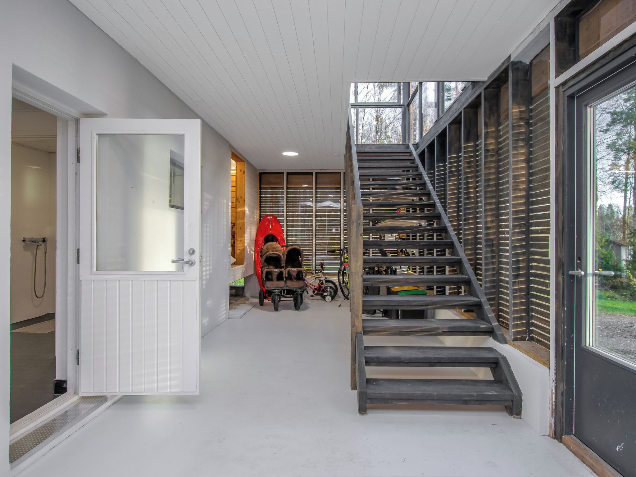 Ein modernes Interieur mit einer Treppe, einer Tür zu einem Badezimmer und einem roten Kajak.