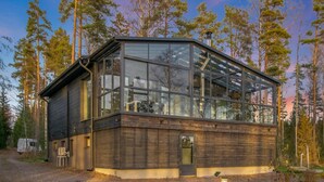 Eine moderne Hütte mit großen Glasfenstern, einer Holzfassade und einem Steinweg zum Eingang.